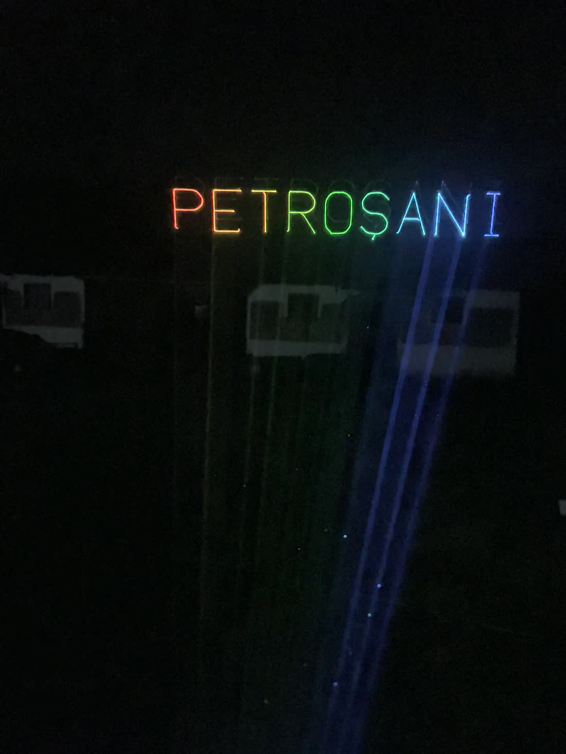Un nume desenat cu laser pe fațada unei clădiri, noaptea